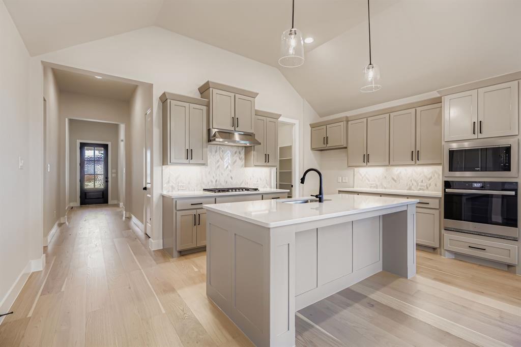 2118 Newhall Road Celina, TX 75009 - Photo 9 of 29 Kitchen featuring stainless steel appliances, tasteful backsplash, pendant lighting, vaulted ceiling, and a kitchen island with sink