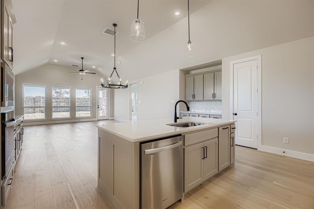 2118 Newhall Road Celina, TX 75009 - Photo 10 of 29 Kitchen with stainless steel appliances, gray cabinetry, decorative backsplash, a chandelier, and an island with sink