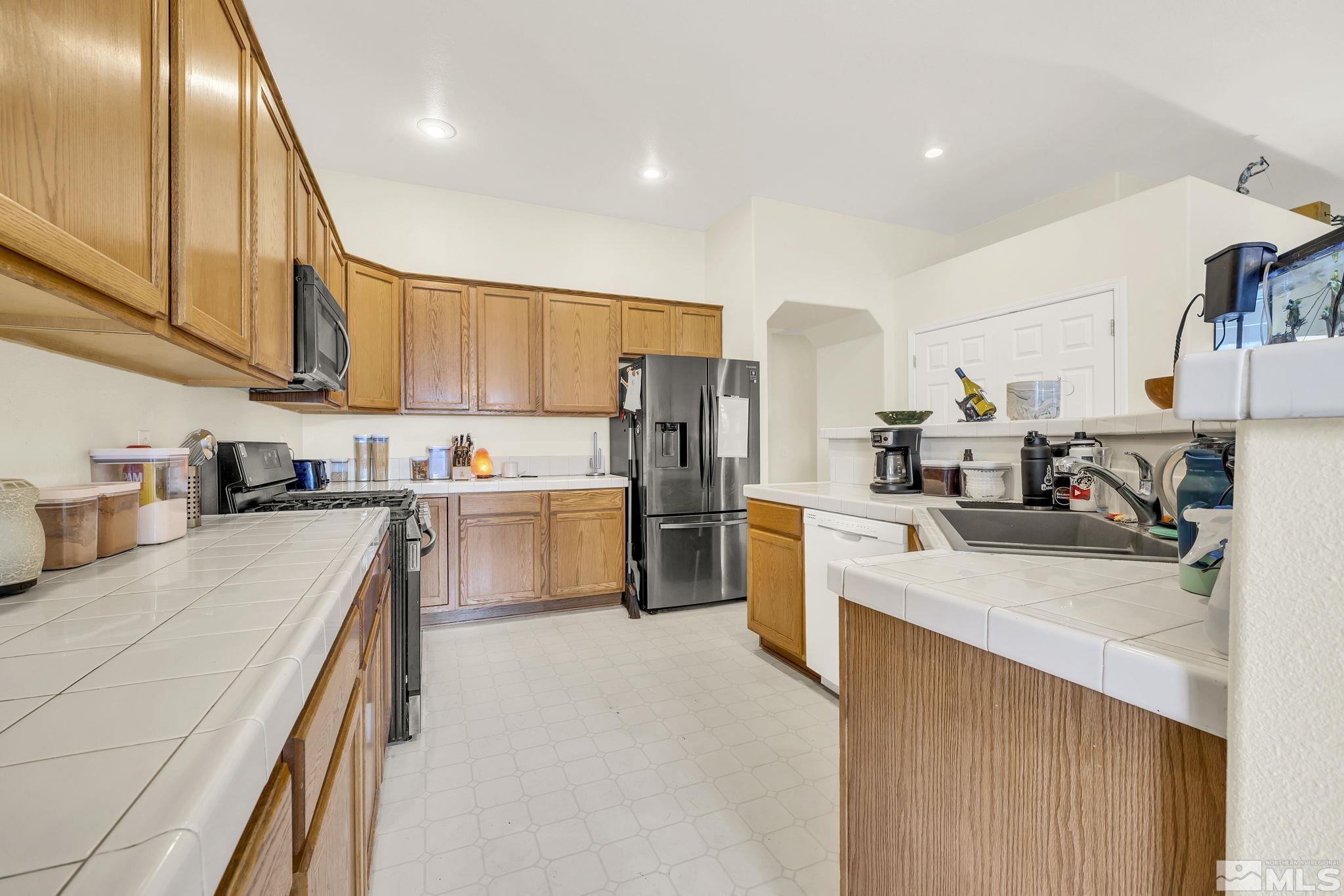 407 Sunshine Lane Fernley, NV 89408 - Photo 17 of 26 a kitchen with white cabinets and stainless steel appliances
