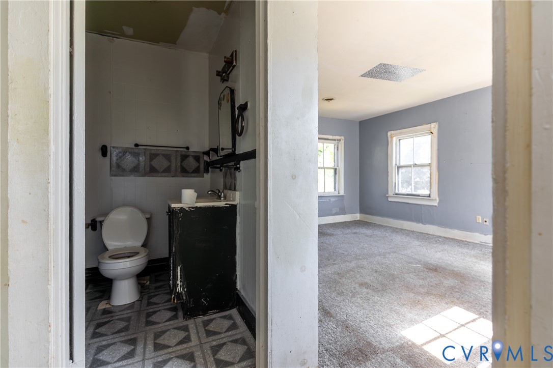 13512 Queen Street Disputanta, VA 23842 - Photo 25 of 46 a bathroom with a granite countertop toilet and a window