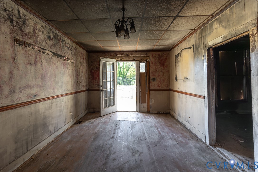 13512 Queen Street Disputanta, VA 23842 - Photo 7 of 46 a view of a hallway with wooden floor and a refrigerator in a kitchen