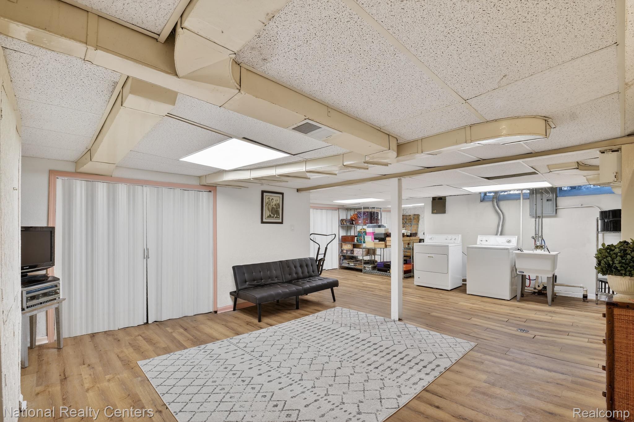 3956 Harvard Road Detroit, MI 48224 - Photo 35 of 44 Finished below grade area with a paneled ceiling, light wood-type flooring, washing machine and dryer, and electric panel