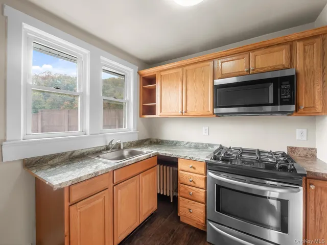 a kitchen with a refrigerator a stove top oven a chimney and living room view