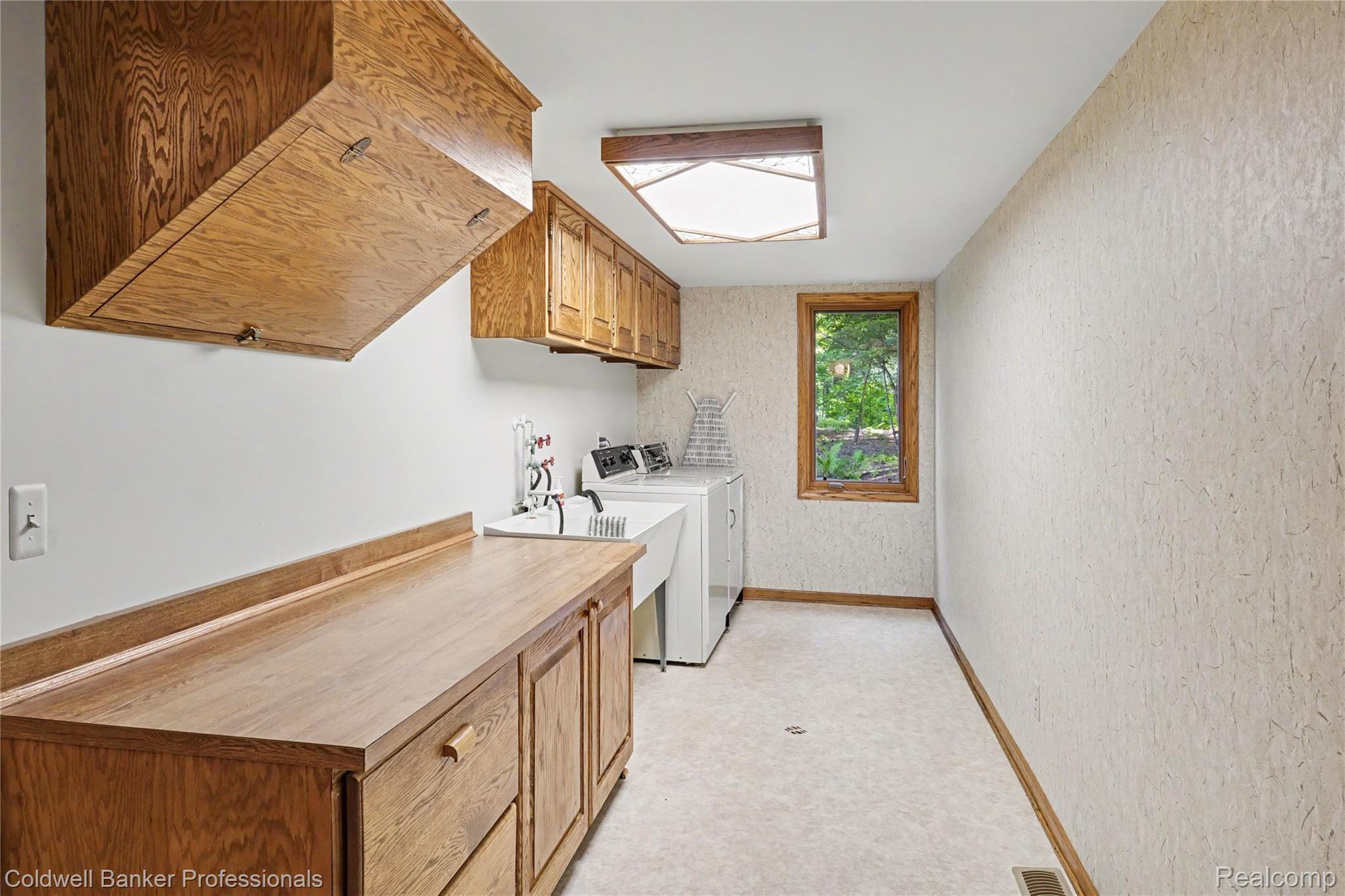 3583 Mitchell Road Metamora, MI 48455 - Photo 44 of 58 Dedicated laundry area featuring a utility sink, wood-finish cabinetry, and a wood-framed window