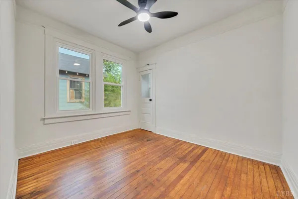a view of empty room with wooden floor and fan