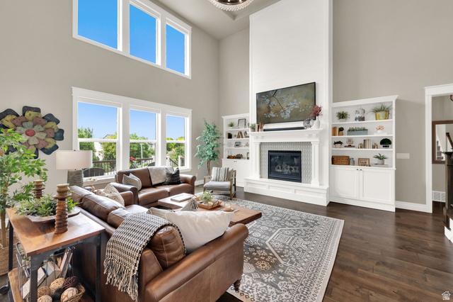 1132 South 1300th Street West Mapleton, UT 84664 - Photo 7 of 52 Spacious living area featuring a tall fireplace with a tiled surround, built-in shelving, wood-finish flooring, and expansive windows