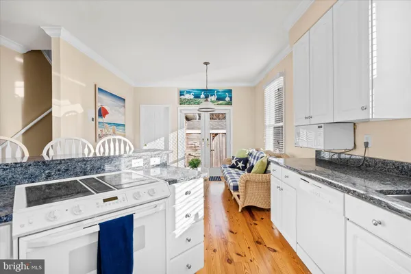 a kitchen with stainless steel appliances granite countertop a stove top oven a sink a dining table and chairs with wooden floor