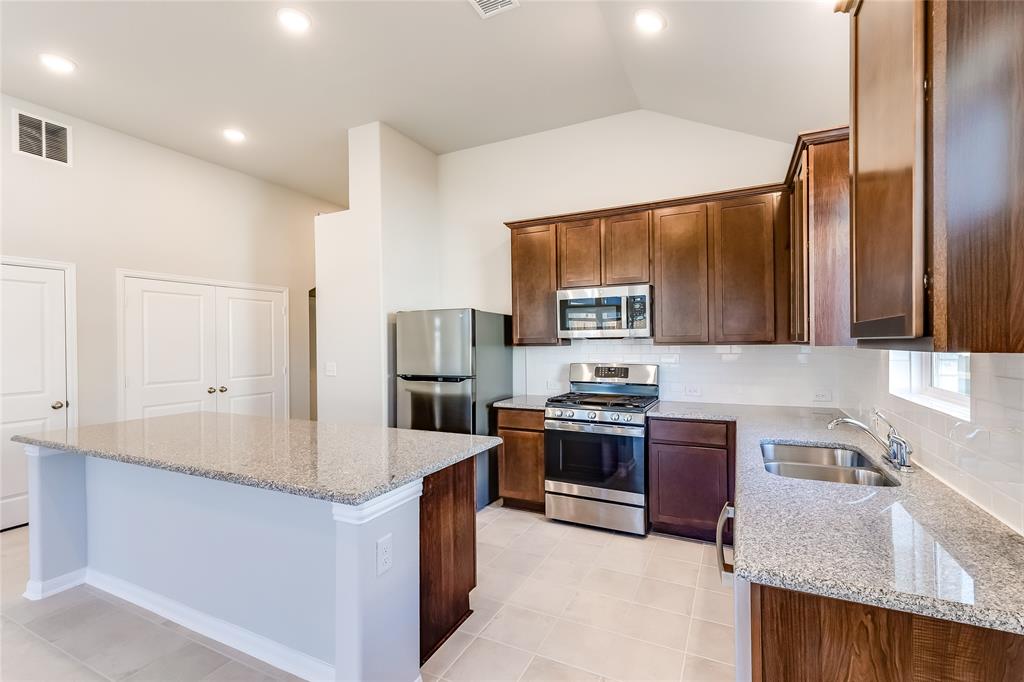 325 Diamondleaf Drive Buda, TX 78610 - Photo 10 of 29 a kitchen with granite countertop a sink stove and refrigerator