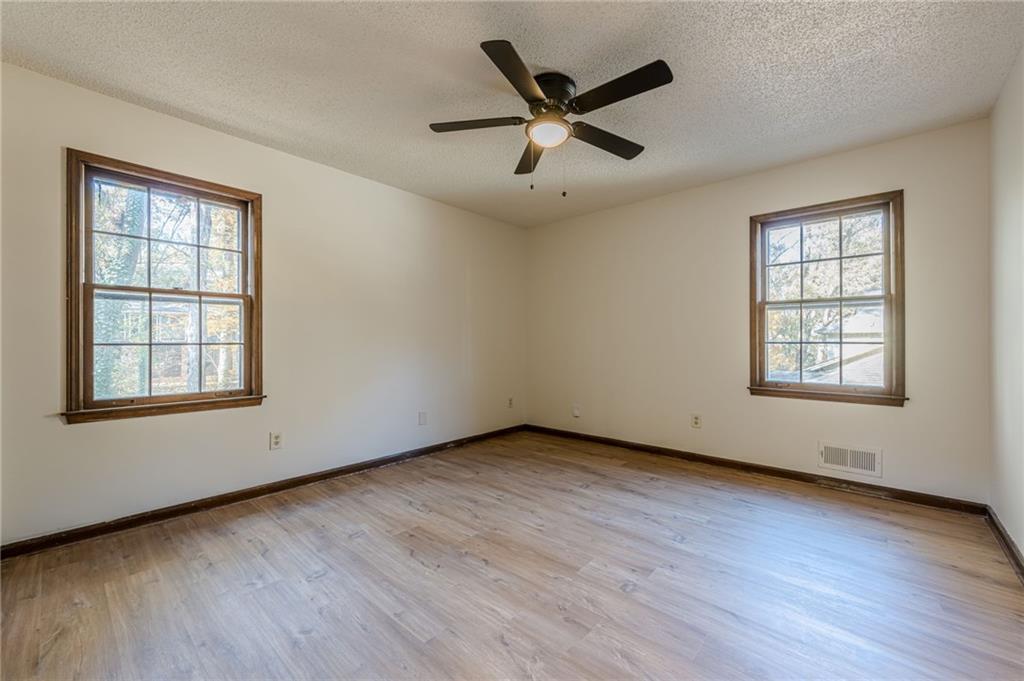 4147 Scofield Place Stone Mountain, GA 30083 - Photo 29 of 56 an empty room with wooden floor fan and windows