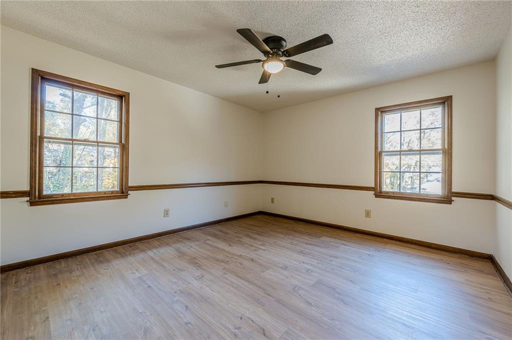 4147 Scofield Place Stone Mountain, GA 30083 - Photo 40 of 56 an empty room with wooden floor fan and windows