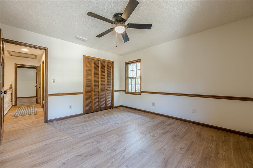 4147 Scofield Place Stone Mountain, GA 30083 - Photo 42 of 56 an empty room with wooden floor chandelier fan and windows