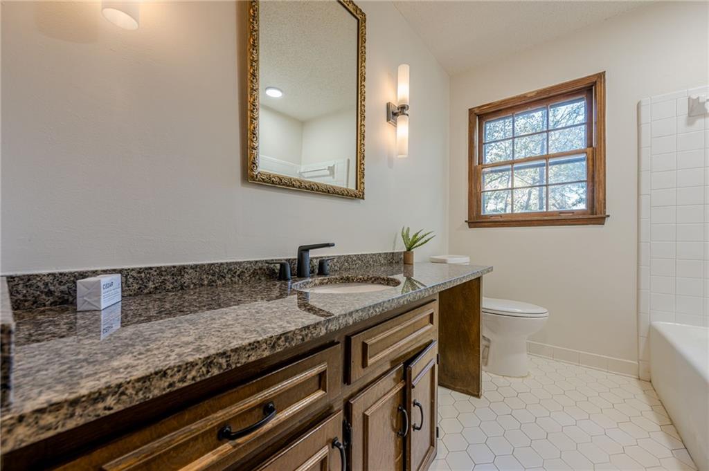 4147 Scofield Place Stone Mountain, GA 30083 - Photo 43 of 56 a bathroom with a granite countertop sink a toilet and mirror