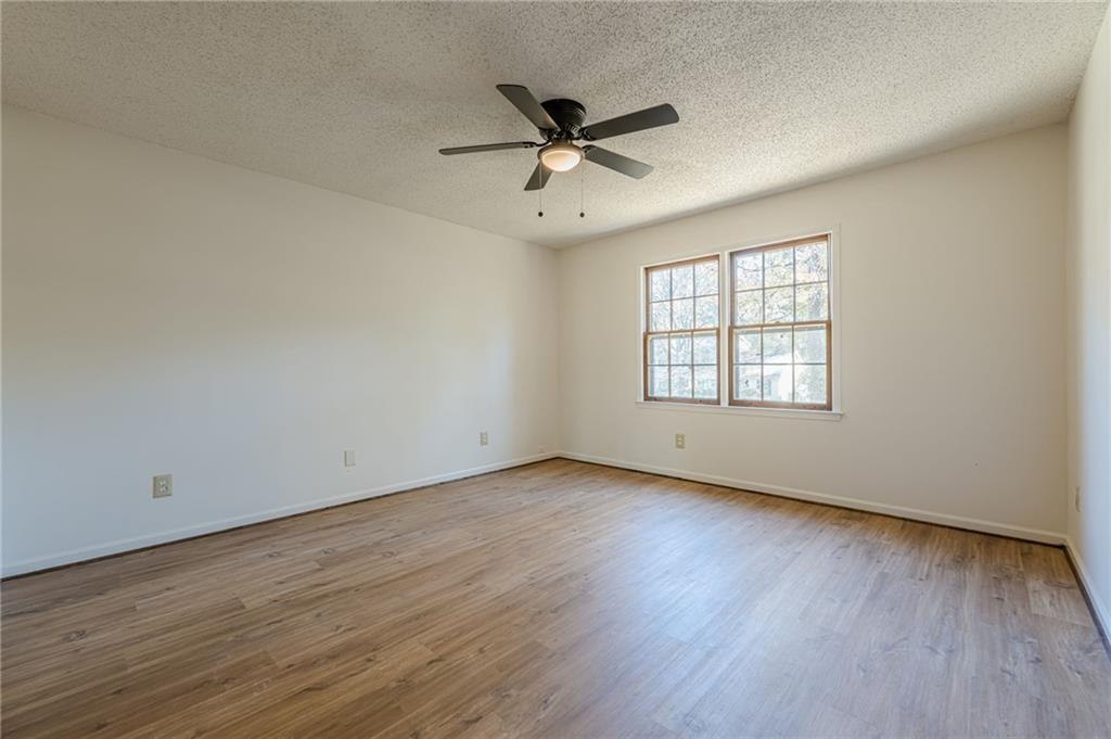 4147 Scofield Place Stone Mountain, GA 30083 - Photo 44 of 56 an empty room with wooden floor a ceiling fan and windows