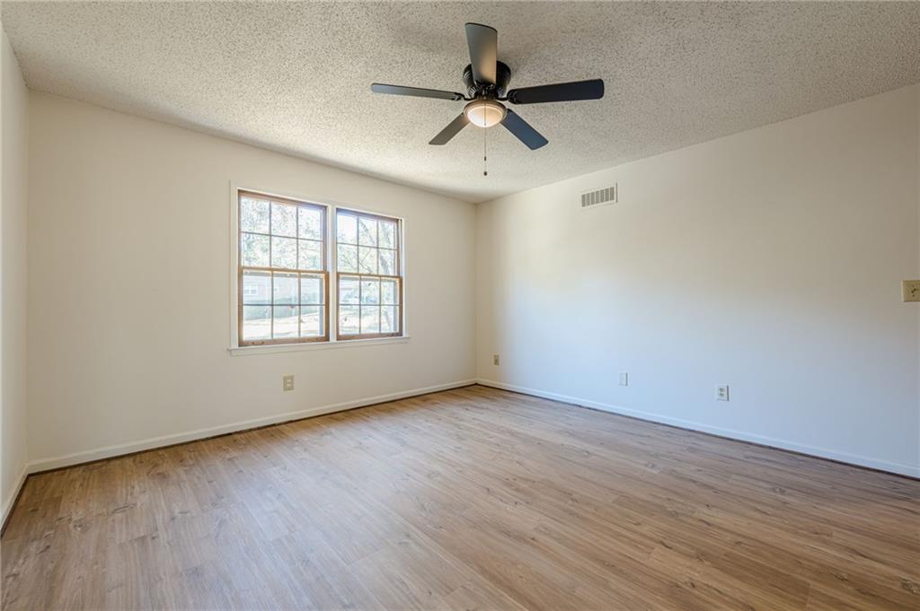 4147 Scofield Place Stone Mountain, GA 30083 - Photo 45 of 56 an empty room with wooden floor fan and windows