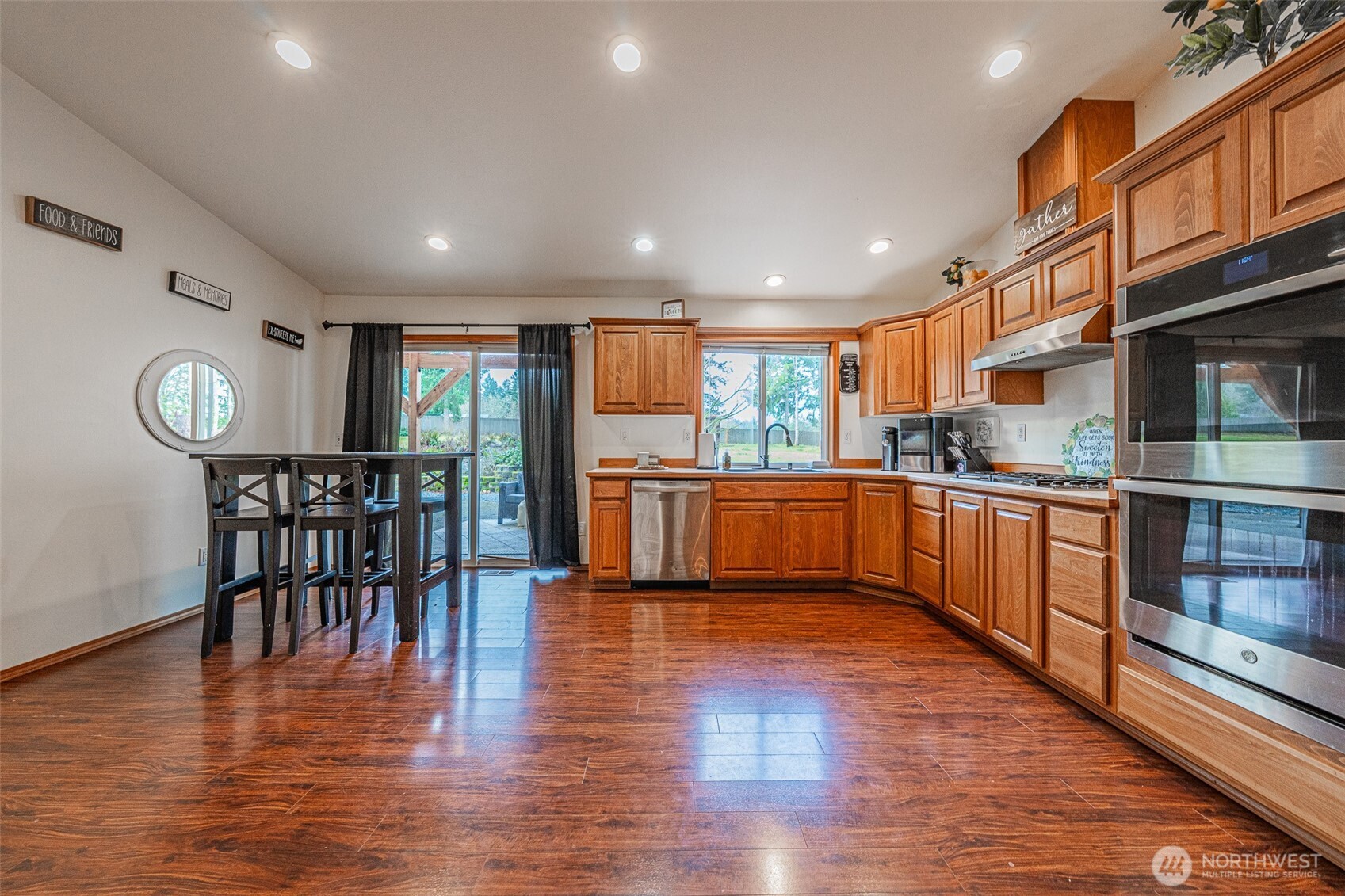 30608 40th Avenue East Graham, WA 98338 - Photo 8 of 30 a kitchen with stainless steel appliances granite countertop a stove top oven a sink and a dining table with wooden floor