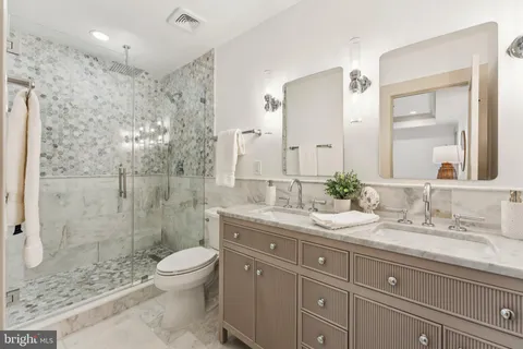 a bathroom with a granite countertop sink toilet a large mirror a shower and vanity