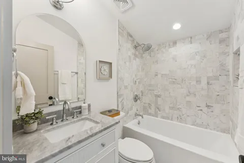 a bathroom with a granite countertop sink mirror toilet and bathtub