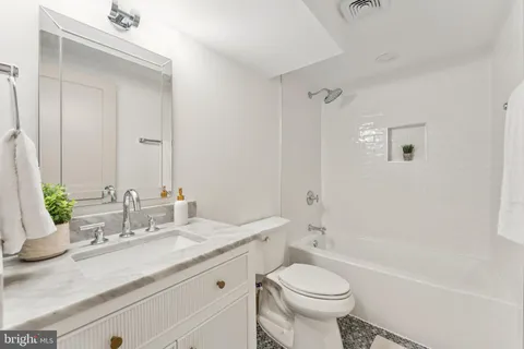 a bathroom with a granite countertop toilet a sink and a bathtub