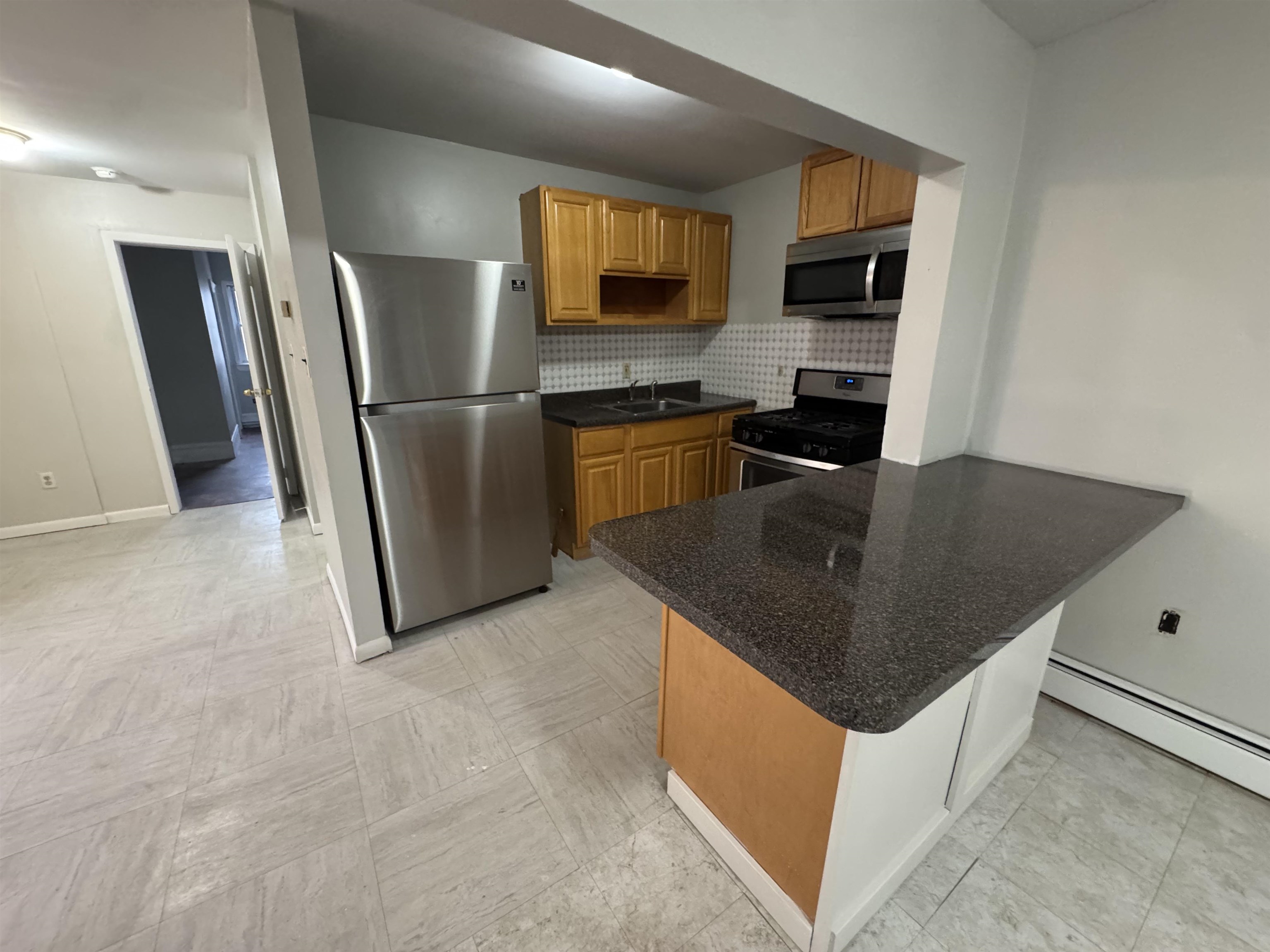 103 Prospect Avenue, Unit 2 Bayonne, NJ 07002 - Photo 2 of 12 a kitchen with stainless steel appliances granite countertop a refrigerator a stove a sink a microwave a counter top and a refrigerator