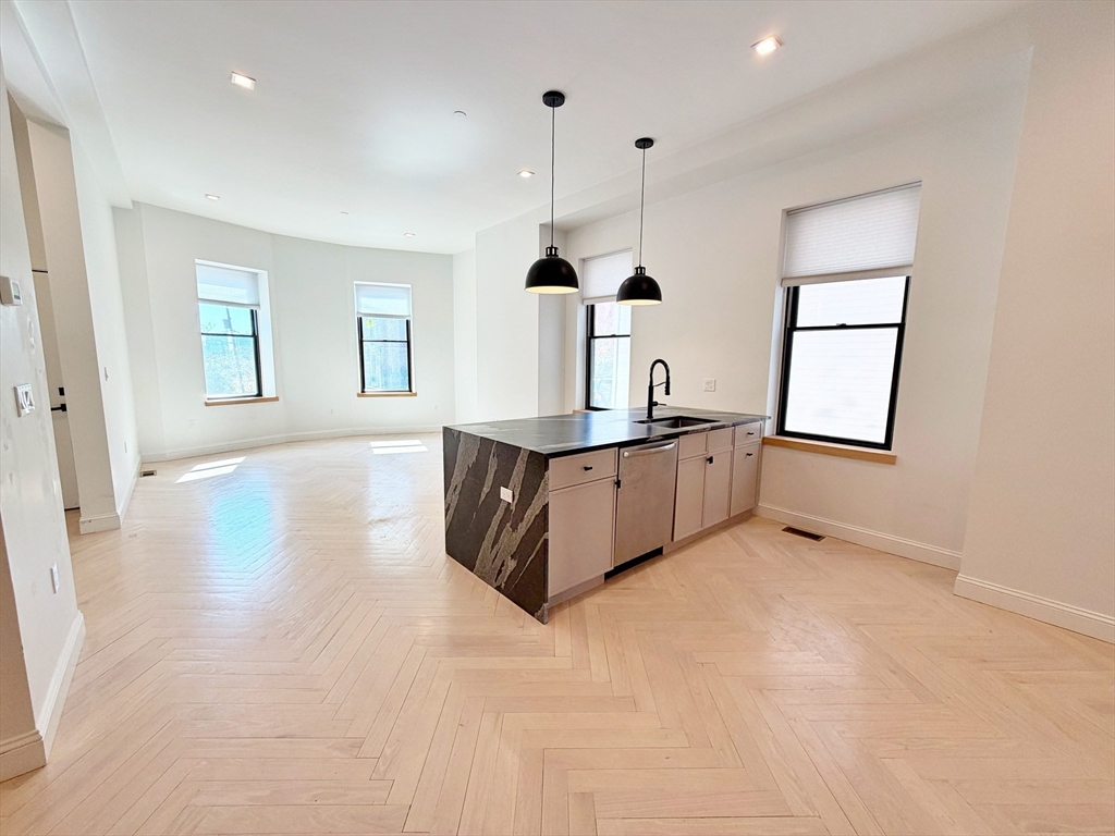 182 Webster Street, Unit 1 Boston, MA 02128 - Photo 11 of 41 a room with kitchen island stainless steel appliances kitchen island granite countertop a sink a window and white cabinets