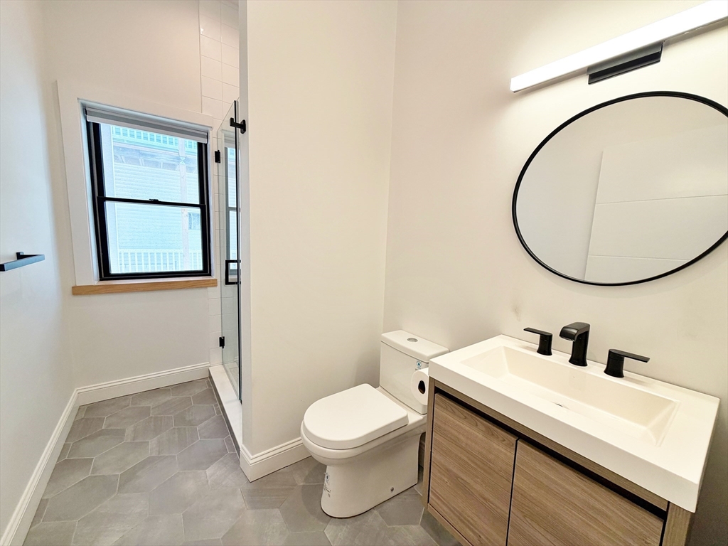 182 Webster Street, Unit 1 Boston, MA 02128 - Photo 22 of 41 a bathroom with a toilet a sink and a mirror