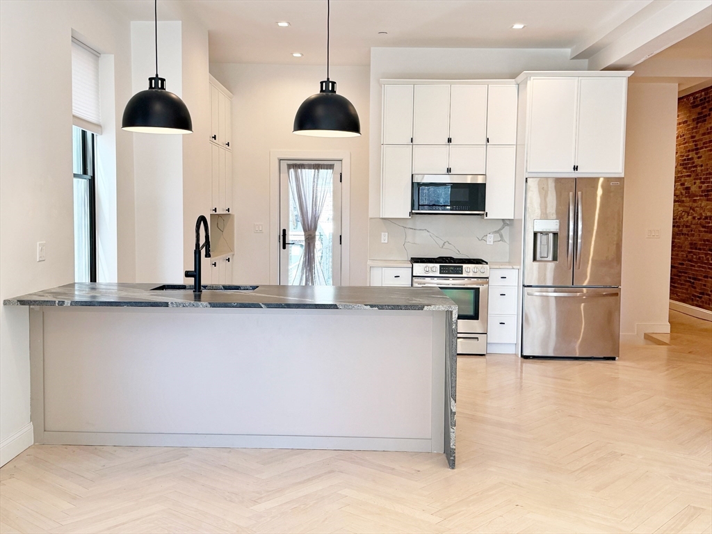182 Webster Street, Unit 1 Boston, MA 02128 - Photo 8 of 41 a kitchen with stainless steel appliances kitchen island granite countertop a refrigerator a stove a sink and white cabinets
