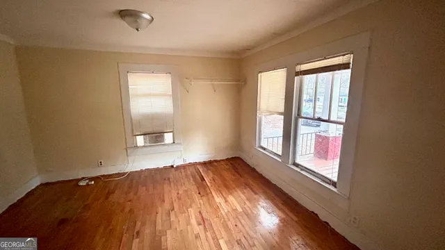 an empty room with wooden floor and windows