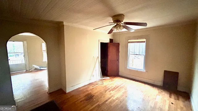 a view of empty room with wooden floor and fan