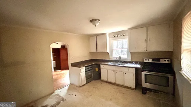 a kitchen with granite countertop a stove top oven sink and cabinets