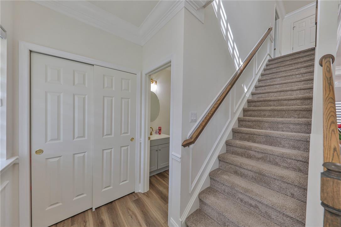1105 Meco Road Easton, PA 18040 - Photo 9 of 100 A carpeted staircase ascends next to a hallway lined with wood flooring and crown molding.