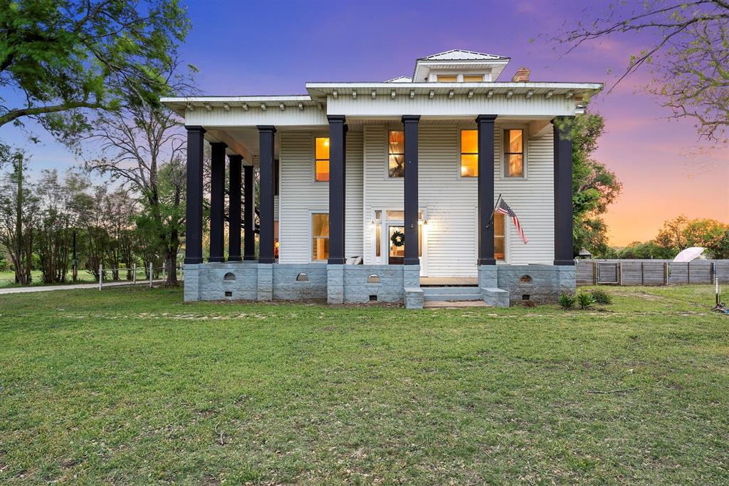 View of front facade featuring fence, a porch, and a yard