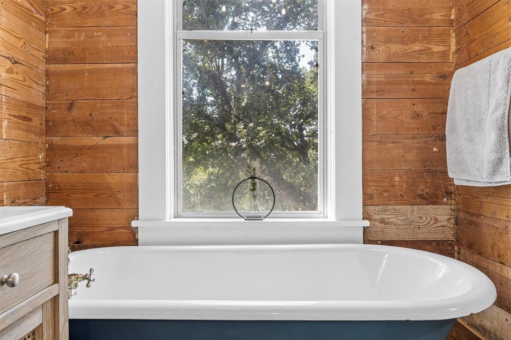 1004 South Old Temple Road Lorena, TX 76655 - Photo 18 of 40 Bathroom featuring wooden walls, a freestanding bath, and vanity