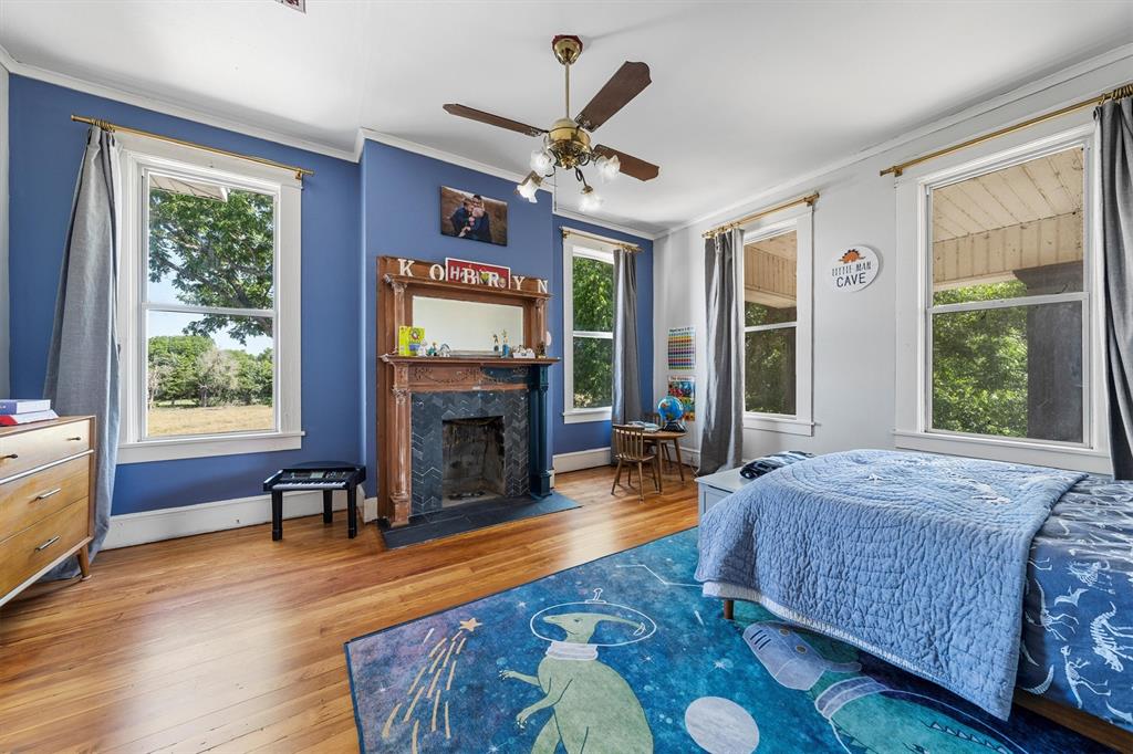 1004 South Old Temple Road Lorena, TX 76655 - Photo 26 of 40 Bedroom featuring crown molding, multiple windows, hardwood / wood-style flooring, and a high end fireplace