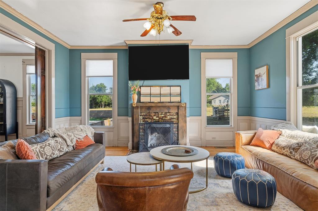 1004 South Old Temple Road Lorena, TX 76655 - Photo 6 of 40 Living area featuring crown molding, wood finished floors, a fireplace, and wainscoting