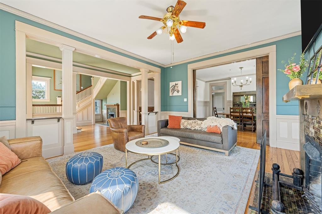 1004 South Old Temple Road Lorena, TX 76655 - Photo 7 of 40 Living area featuring a wainscoted wall, ornate columns, wood finished floors, and ceiling fan with notable chandelier