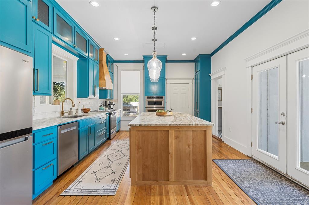 1004 South Old Temple Road Lorena, TX 76655 - Photo 10 of 40 Kitchen with light wood-style floors, a kitchen island, appliances with stainless steel finishes, blue cabinets, and backsplash