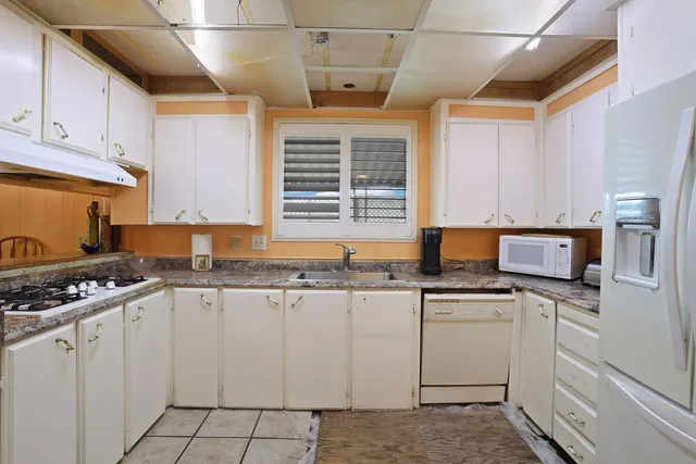a kitchen with granite countertop white cabinets and white appliances