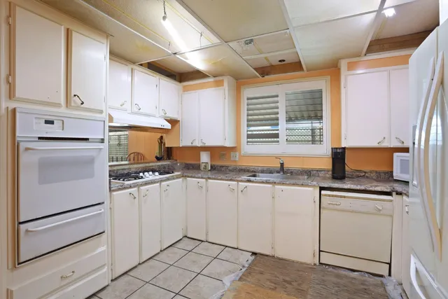 a kitchen with granite countertop white cabinets and white appliances