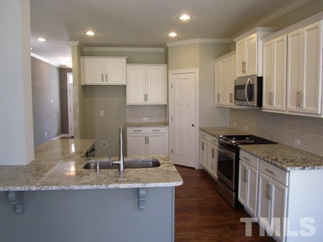 1644 Forest Road Wake Forest, NC 27587 - Photo 5 of 23 Well appointed kitchen w/ site finished hardwoods, granite c-tops, under cabinet lighting, recessed lights, tile backsplash, walk in pantry and stainless appliances