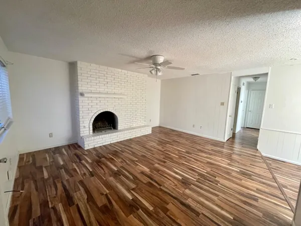 a view of empty room with wooden floor and fireplace