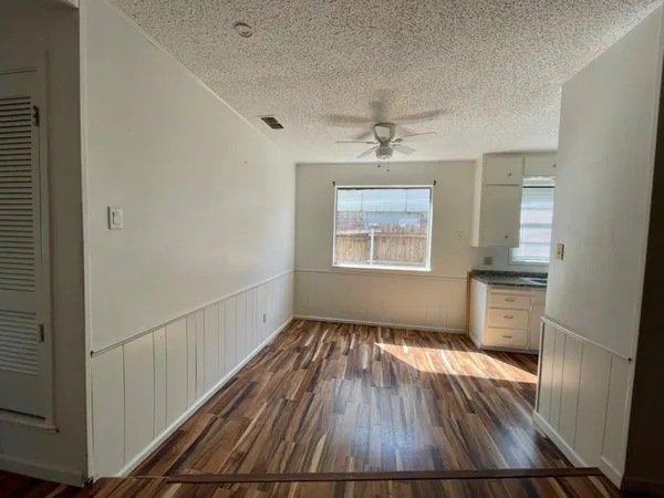 a view of an empty room with a window and wooden floor