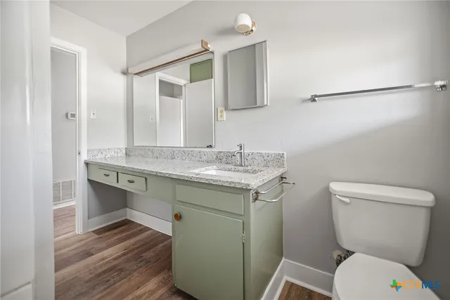 a bathroom with a granite countertop toilet sink and mirror