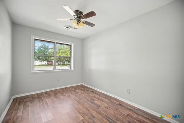 an empty room with a window and wooden floor