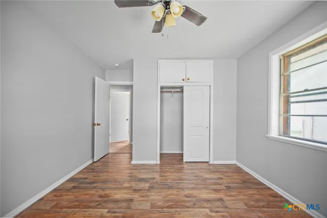 a view of empty room with wooden floor and window