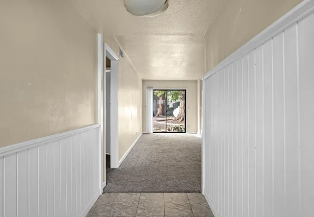 a view of hallway with window and wooden floor