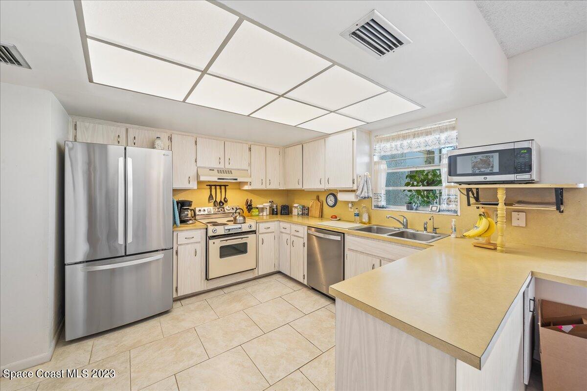 435 Dove Lane, Unit 810 Satellite Beach, FL 32937 - Photo 6 of 43 a kitchen with stainless steel appliances granite countertop a refrigerator a stove a sink dishwasher and a refrigerator