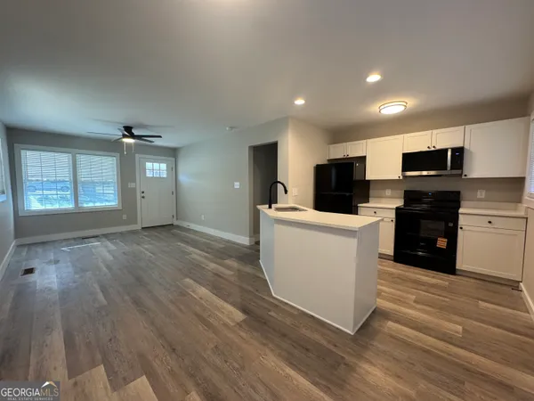 a view of kitchen with stainless steel appliances granite countertop a stove top oven a sink dishwasher and a refrigerator with wooden floor
