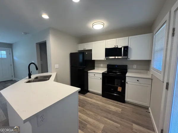 a view of a hallway with wooden floor and a bathroom