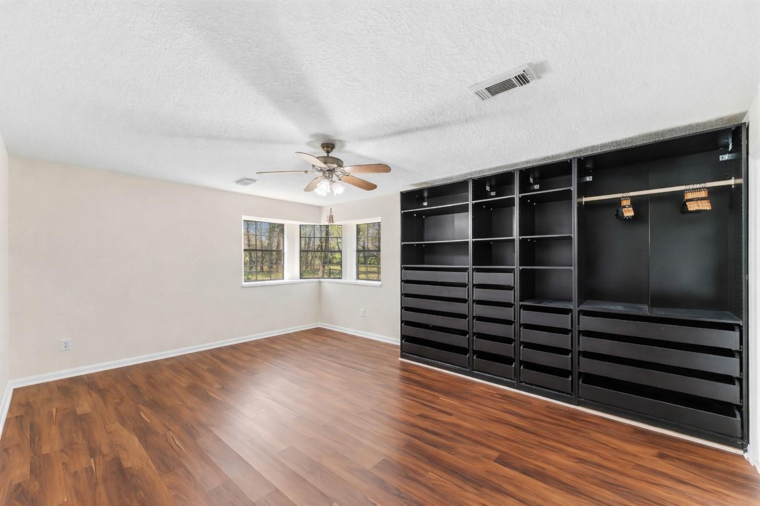 7825 Hughes Ranch Road Pearland, TX 77581 - Photo 13 of 28 The primary suite offers a calm and spacious escape — warm wood-look flooring, a beautiful arched window, and a clean, airy layout designed for rest and privacy.