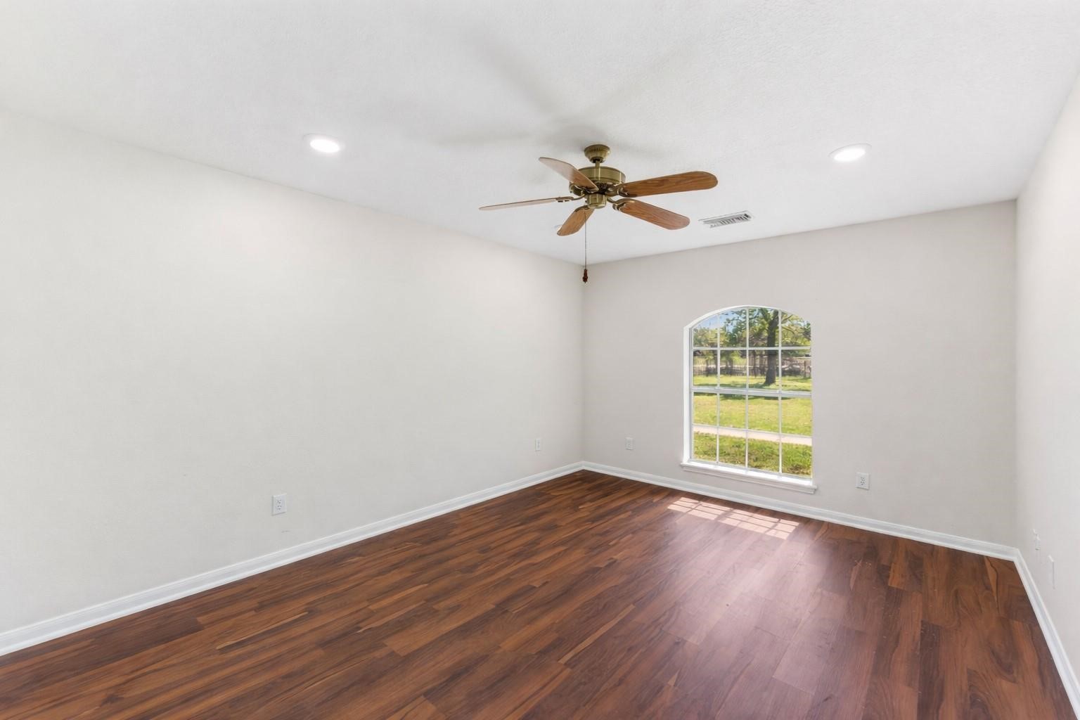 7825 Hughes Ranch Road Pearland, TX 77581 - Photo 15 of 28 well-sized secondary bedroom with warm wood-look flooring, great natural light, and a comfortable layout with ample closet space — ready for family, guests, or whatever life calls for.